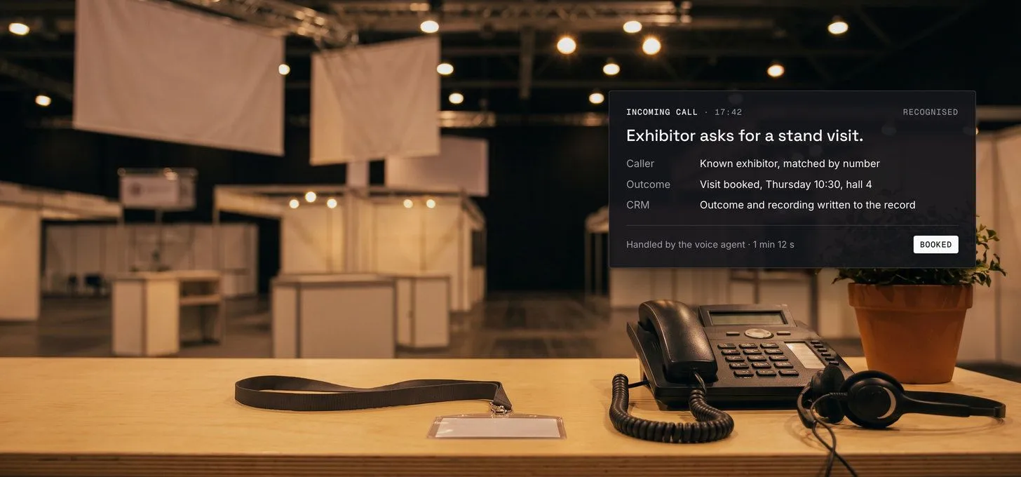 An exhibitor counter at a trade fair after hours with a desk phone and headset, and a call card showing a booked stand visit written to the CRM.